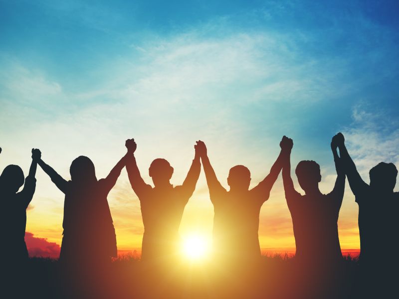 Image of people holding hands in air at sunrise