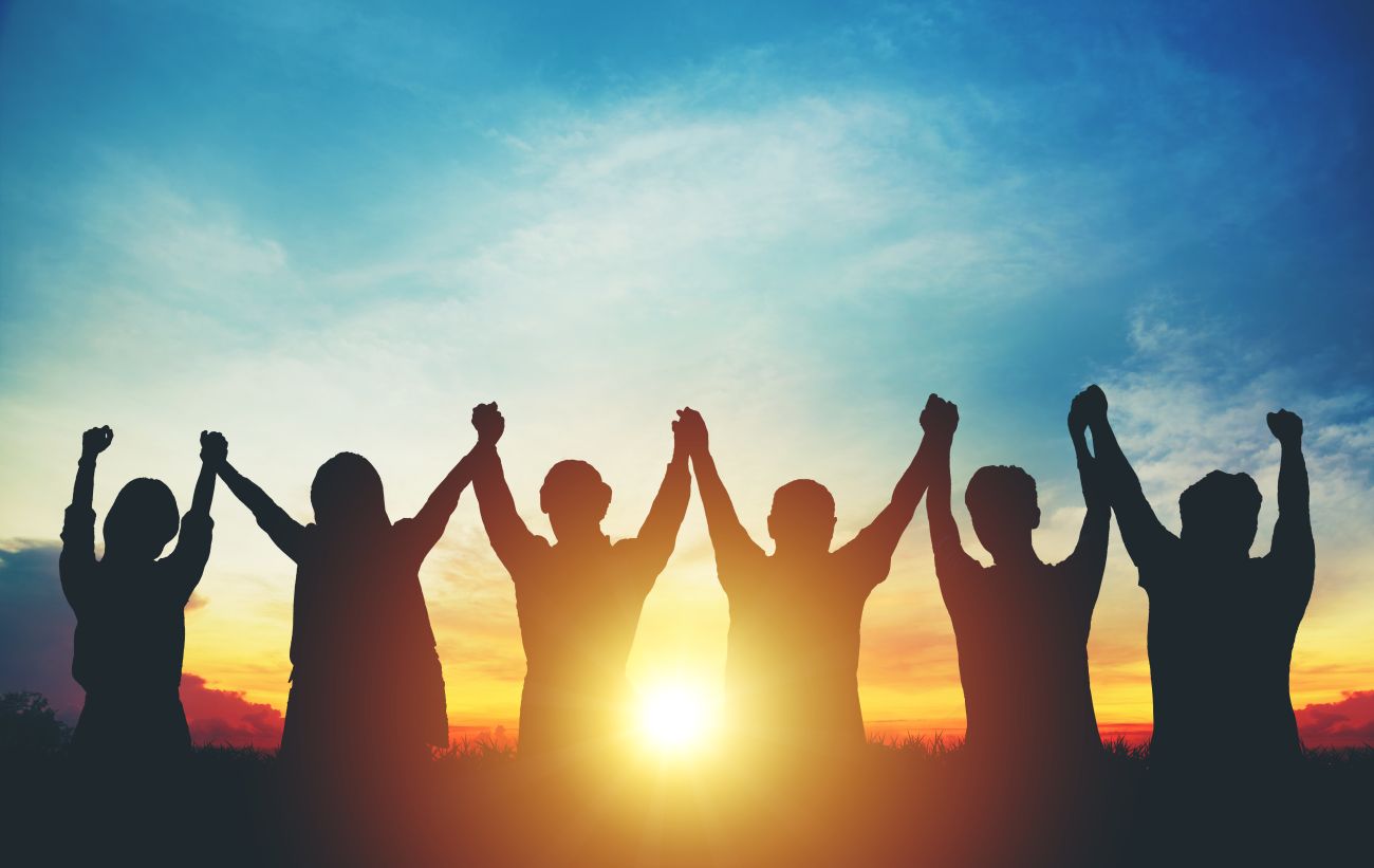 Image of people holding hands in air at sunrise